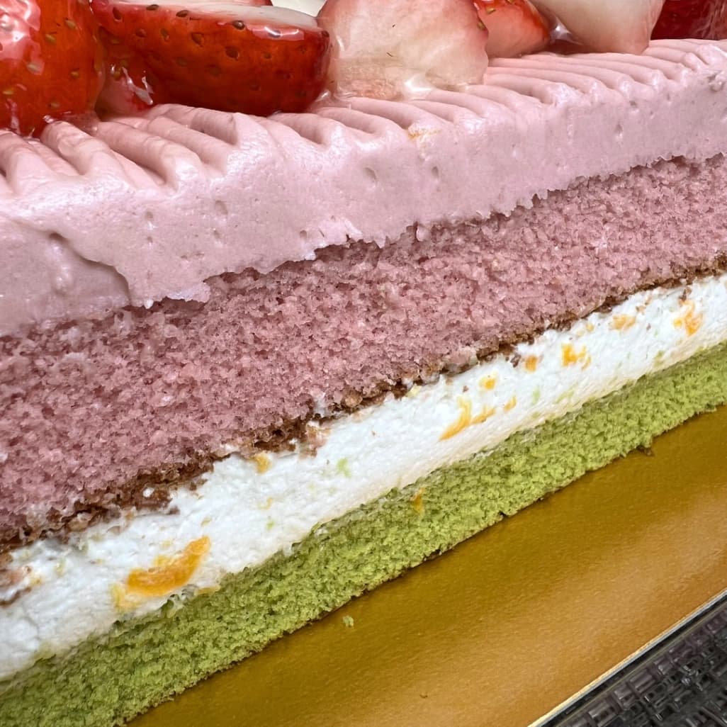 コストコのスプリングバーケーキの断面アップ。ピンクスポンジと白クリーム、緑スポンジの層