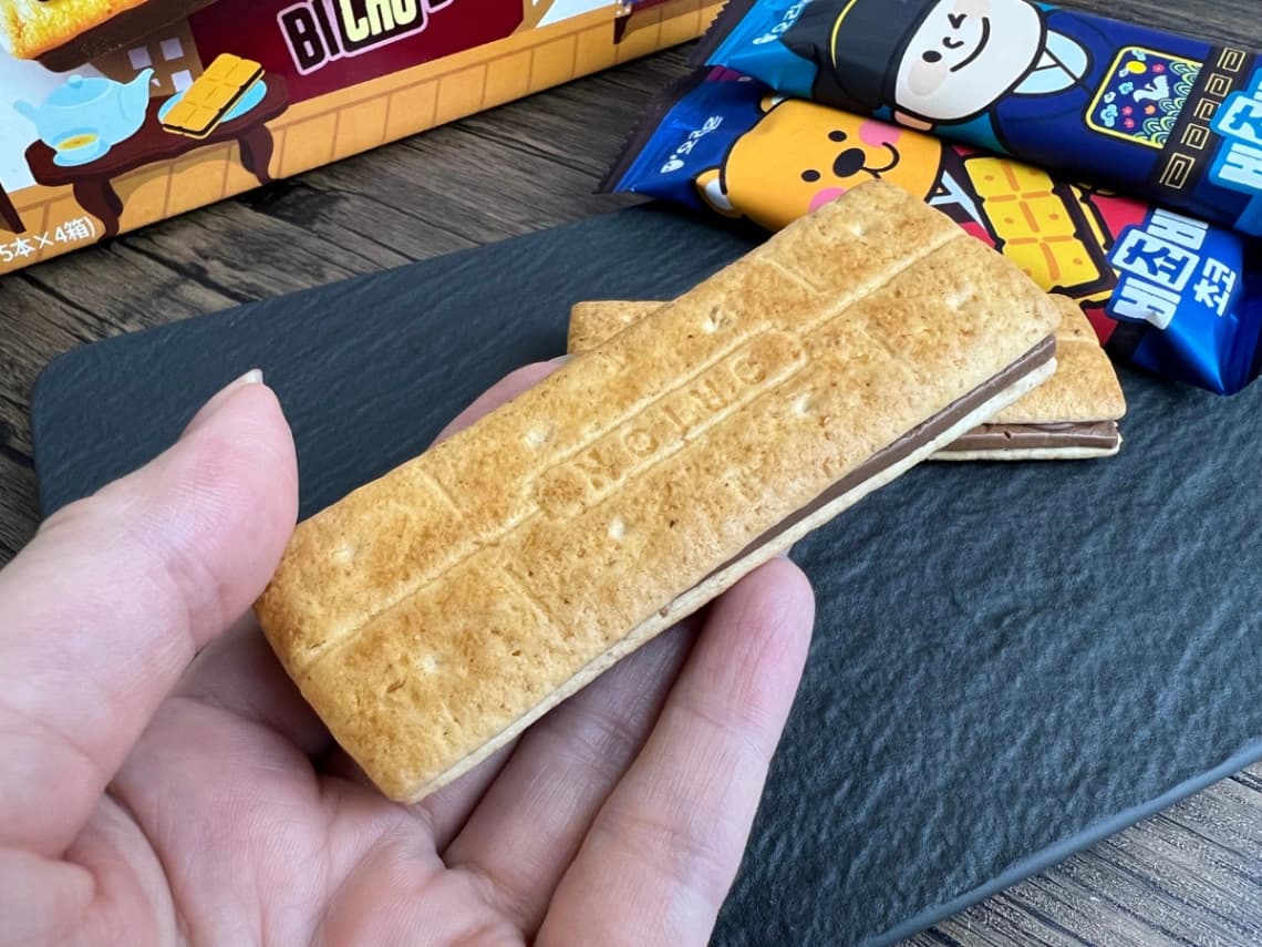 コストコのMarket O「ビチョビ」を手に持ってサイズ感を比較。長方形のビスケットと間に挟まれた厚いチョコレートがわかる実物写真