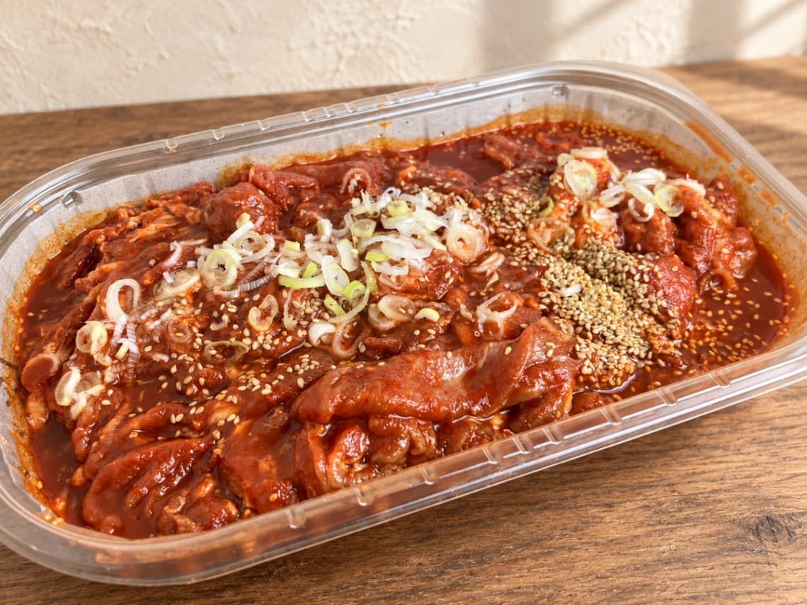 コストコのコチュジャンポークプルコギを開封した様子。甘辛い赤いタレに豚肉と長ねぎ、ごまがたっぷり入っている