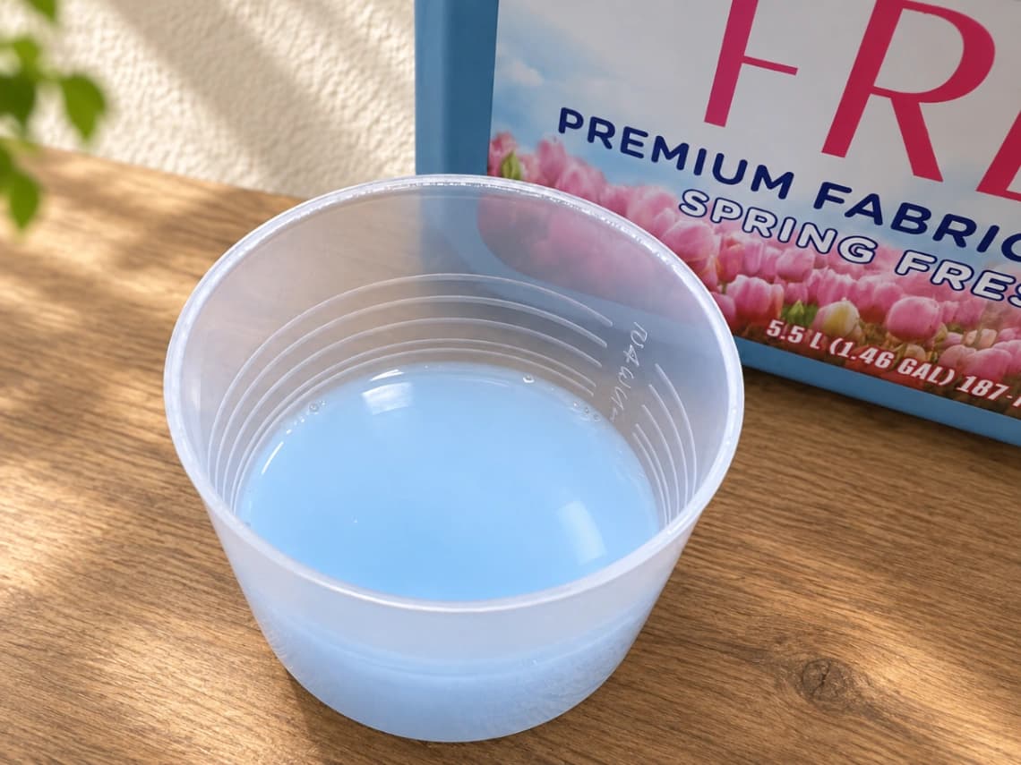コストコ カークランド ウルトラフレッシュ柔軟剤の水色の液体を入れた計量カップ