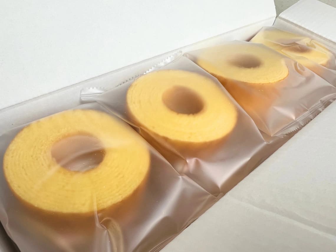 コストコ「千年屋 おとなのばうむ。ゆず」の箱を開封した様子。個包装されたゆず風味のバウムクーヘンが並んでいる