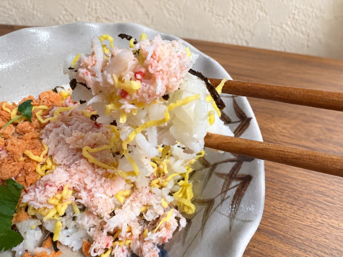 コストコ「蟹と鮭のちらし寿司」ずわい蟹・錦糸卵・酢飯を箸で持ち上げた様子