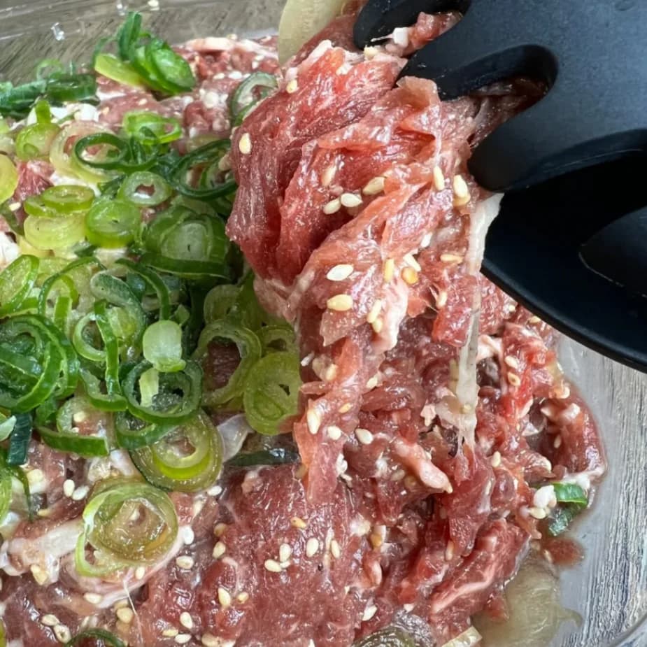 コストコのプルコギビーフをトングで持ち上げた様子｜味付き牛肉のやわらかさがわかる写真