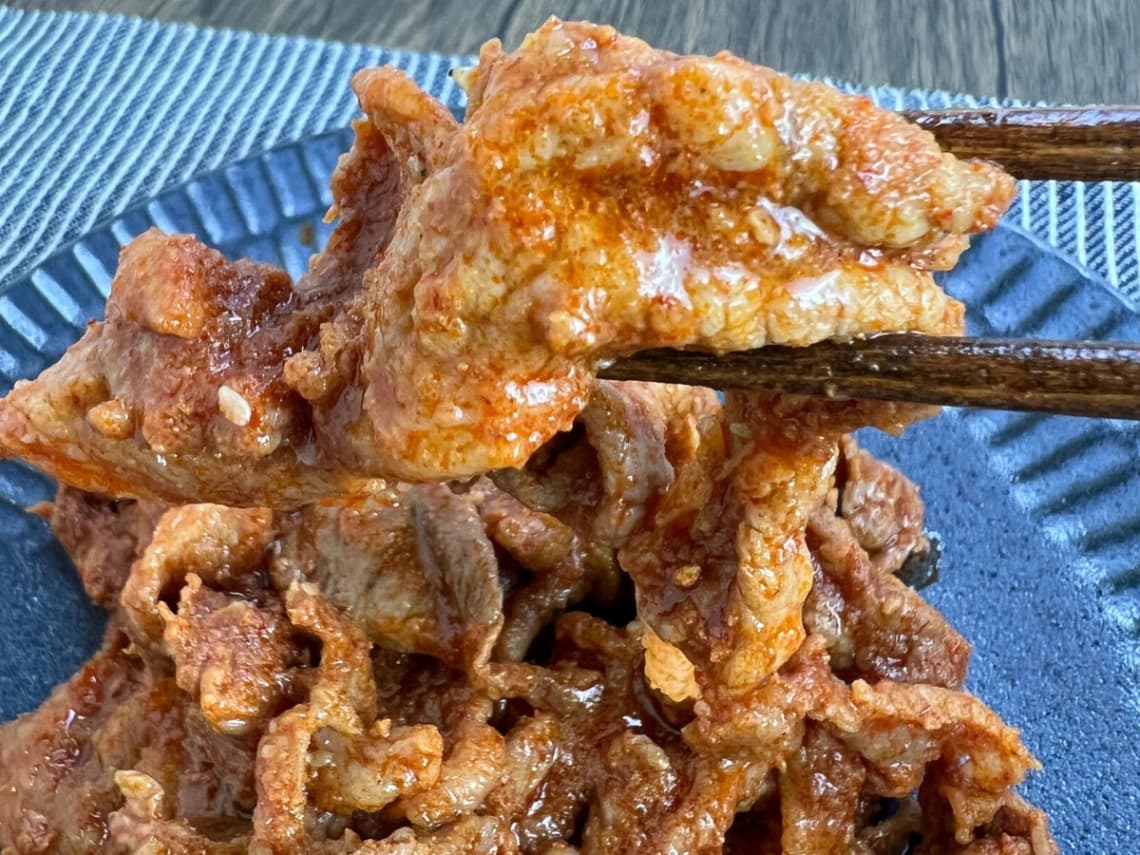 焼いたコストコのコチュジャンポークプルコギを箸で持ち上げた実食写真。甘辛いタレが絡んだやわらかい豚肉