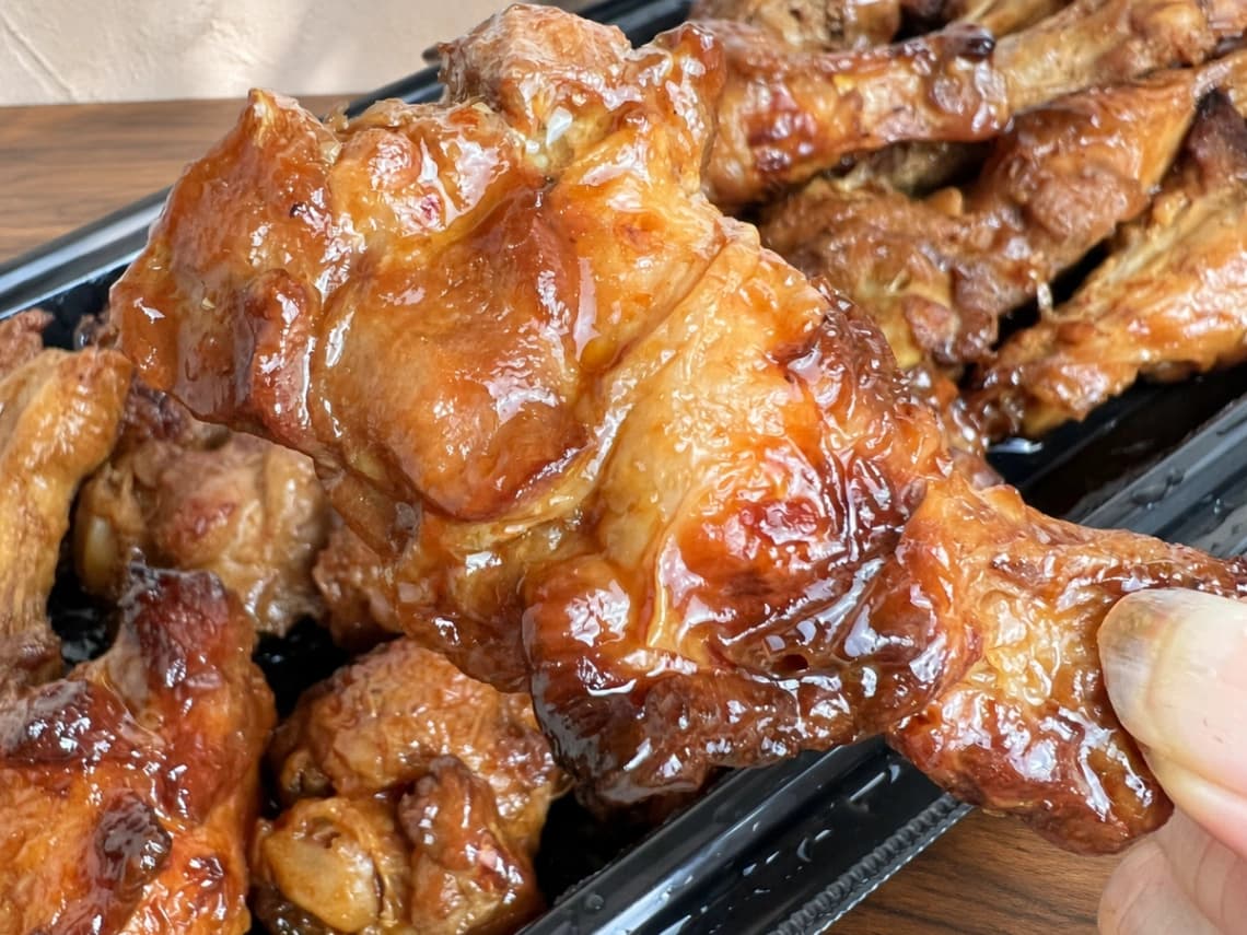 コストコBBQチキンを手に持った様子｜ツヤのある甘辛ソースの手羽元